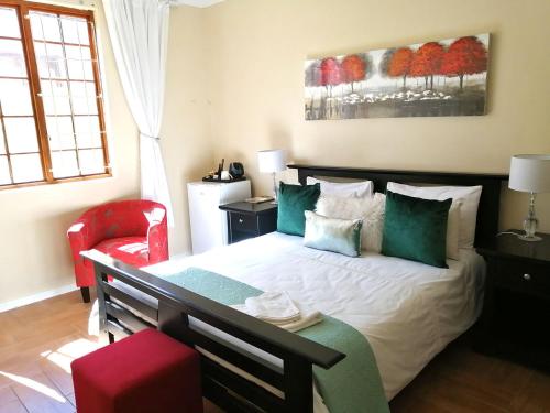 a bedroom with a large bed and a red chair at 5 on Jameson Guesthouse in Quigney