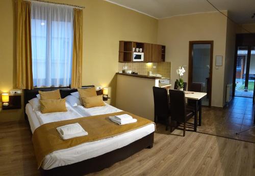 a hotel room with a large bed and a kitchen at Gellény Lux Apartman in Gyula