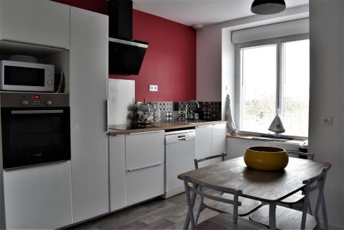 - une cuisine avec des placards blancs et une table avec un bol dans l'établissement Gîte de la Roche - Grande maison bretonne, à Lannilis