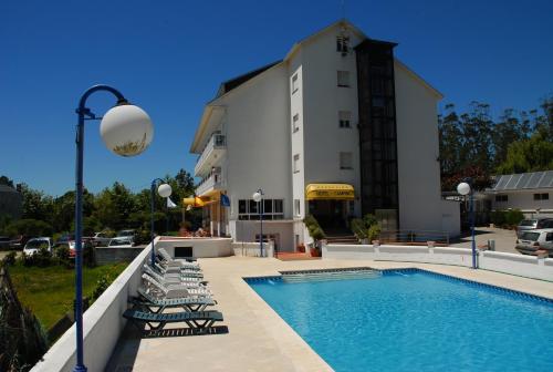 a pool with lounge chairs next to a building at Hotel Arco Iris in Villanueva de Arosa