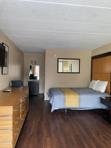 溫徹斯特的住宿－APM Inn and Suites，一间卧室配有一张床、梳妆台和电视。