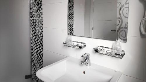 a white bathroom with a sink and a mirror at Hostal Doña Isabel in Majadahonda