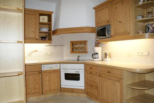 a kitchen with wooden cabinets and a white stove top oven at Ferienwohnung Bluntaumühle in Golling an der Salzach