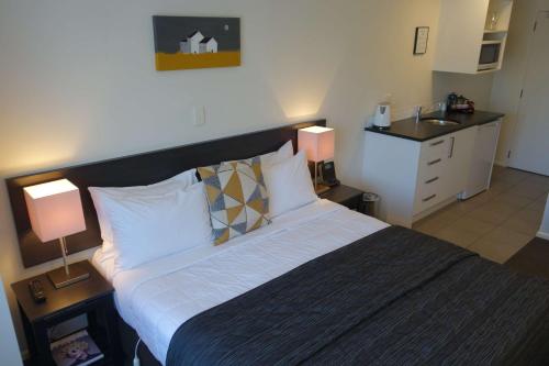 a bedroom with a large bed and a sink at Airport Palms Motel in Christchurch