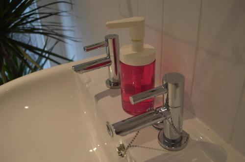 a bathroom sink with a red soap dispenser on it at 8 bed house 2 miles (7 Mins) from Newcastle centre in Newcastle upon Tyne