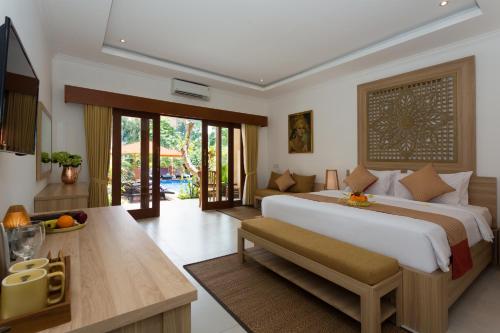 a bedroom with a large bed and a living room at Puri Payogan Villa in Ubud