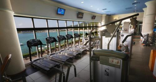 a gym with a row of treadmills and the ocean at Half Moon Bay Motel in Auckland