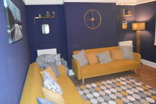 a living room with two couches and a clock on the wall at 9 bed house (7 Mins) 2 miles from Newcastle centre in Newcastle upon Tyne