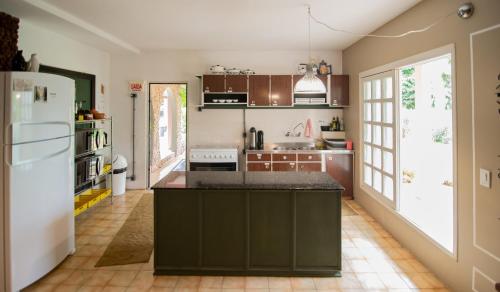 a kitchen with brown cabinets and a white refrigerator at Acasarosa Hostel in Praia Grande