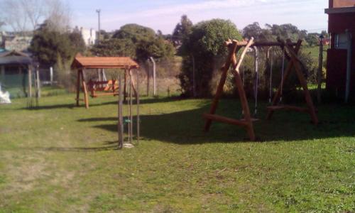a playground with two swings in a yard at Complejo de Cabañas lo de Otto , Los Acantilados , Mar del plata in Mar del Plata