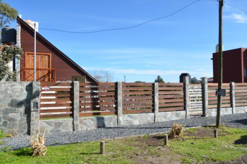 a wooden fence in front of a house at Complejo de Cabañas lo de Otto , Los Acantilados , Mar del plata in Mar del Plata