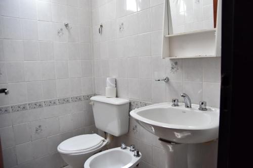 a white bathroom with a toilet and a sink at El Indalo in Embalse