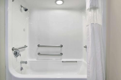 a bathroom with a bath tub with a shower curtain at Howard Johnson by Wyndham Allentown/Dorney Hotel & Suites in Allentown