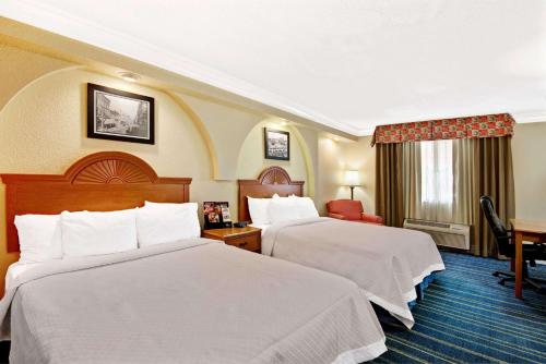 a hotel room with two beds and a desk at Days Inn by Wyndham San Antonio Airport in San Antonio