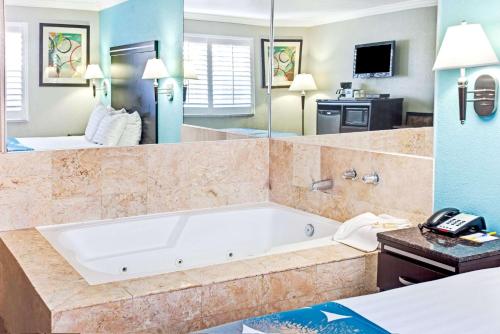 a bath tub in a room with a bedroom at Cabana Inn & Suites in Long Beach