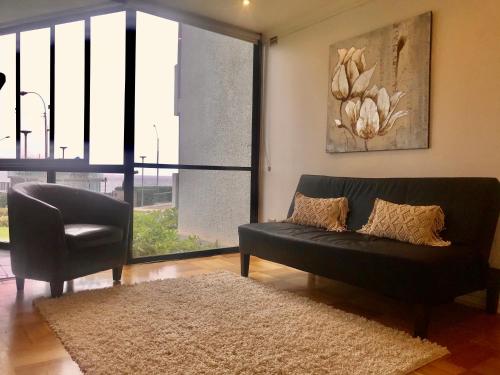 a living room with a black couch and a chair at Departamento en Playa Acapulco viña del mar in Viña del Mar