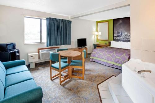 a hotel room with a bed and a table and chairs at Super 8 by Wyndham Mokena/Frankfort /I-80 in Mokena