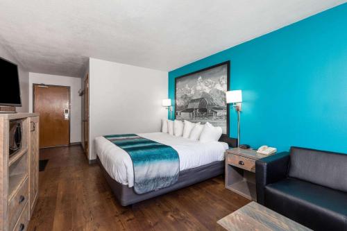a hotel room with a large bed and a couch at Super 8 by Wyndham Gardiner/Yellowstone Park Area in Gardiner