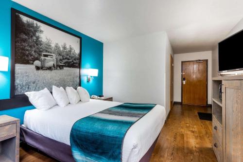 a hotel room with a large bed with a large picture on the wall at Super 8 by Wyndham Gardiner/Yellowstone Park Area in Gardiner