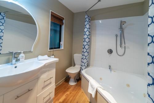 a bathroom with a sink and a tub and a toilet at Overton Cottage - Akaroa Holiday Home in Akaroa