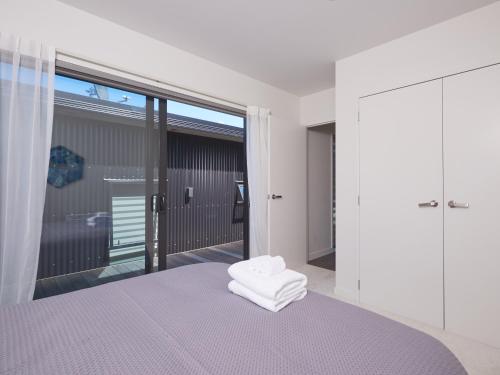 - une chambre avec un lit et une grande fenêtre dans l'établissement Southern Lakes Spa - Queenstown Apartment R2, à Queenstown