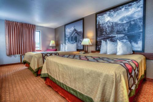 a hotel room with two beds and a large painting on the wall at Super 8 by Wyndham Jackson Hole in Jackson