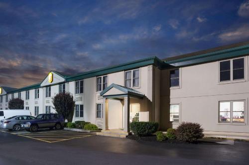 a large white building with a car parked in a parking lot at Super 8 by Wyndham Harrisburg Hershey West in Harrisburg