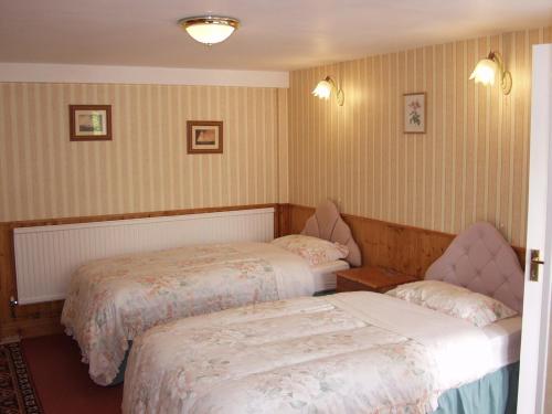a bedroom with two beds and two chairs at The Coach House in Ledbury