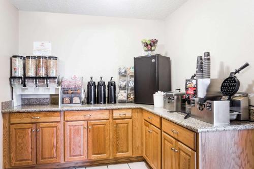 a kitchen with wooden cabinets and a black refrigerator at Super 8 by Wyndham Lewistown in Lewistown