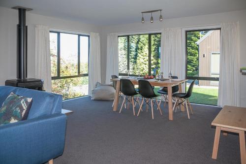 a living room with a blue couch and a table and chairs at Treetop Lodge - Acheron Holiday Home in Hanmer Springs