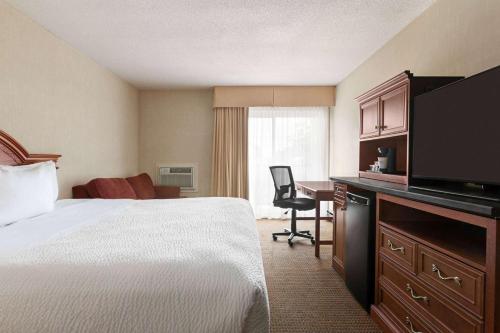 a hotel room with a bed and a desk with a television at Days Inn by Wyndham London in London
