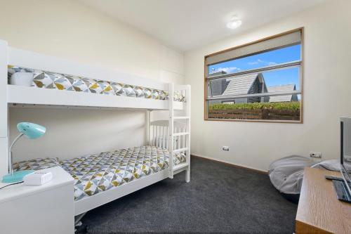 ein Schlafzimmer mit Etagenbetten und einem Fenster in der Unterkunft Infinity Views - Modern Wanaka Holiday Home in Wanaka