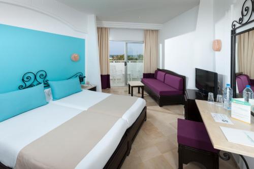 um quarto de hotel com uma cama grande e um sofá em Palm Beach Club Marmara Djerba em Midoun