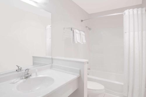 Baño blanco con lavabo y aseo en Days Inn by Wyndham Portage, en Portage