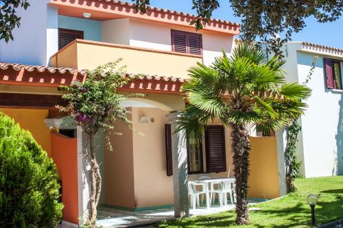a house with palm trees in front of it at Residence Oasi Anfiteatro in Porto Ottiolu