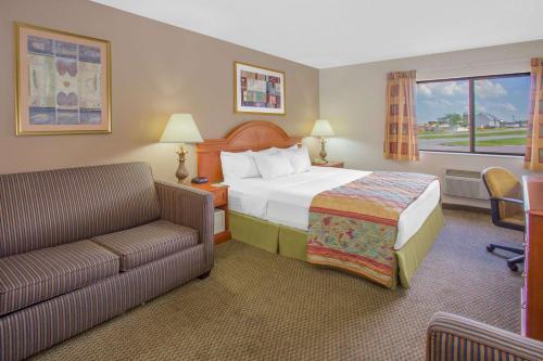 Habitación de hotel con cama y sofá en Days Inn by Wyndham Portage, en Portage