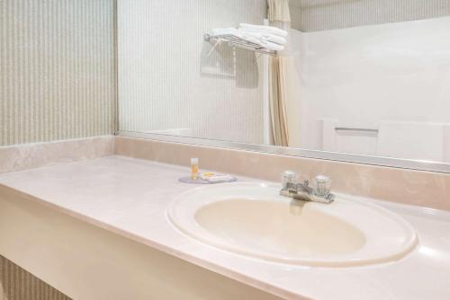 een badkamer met een witte wastafel en een spiegel bij Days Inn by Wyndham Topeka in Topeka