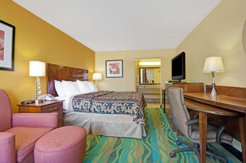 a hotel room with a bed and a desk at Days Inn by Wyndham Norfolk Military Circle in Norfolk