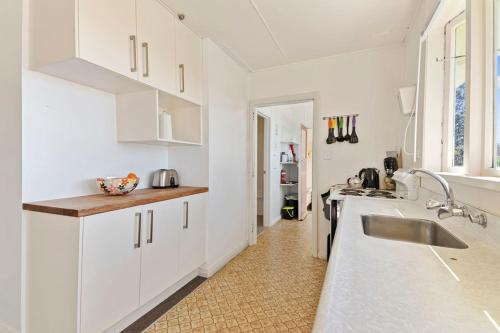 a white kitchen with a sink and a counter at Pakawau Beach House - Golden Bay Holiday Home in Pakawau