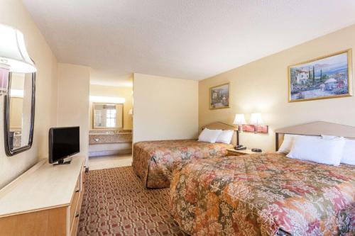 a hotel room with two beds and a flat screen tv at Days Inn by Wyndham Yazoo City in Yazoo City