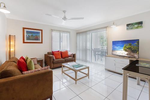 a living room with a couch and a tv at Outrigger Apartments Port Douglas in Port Douglas