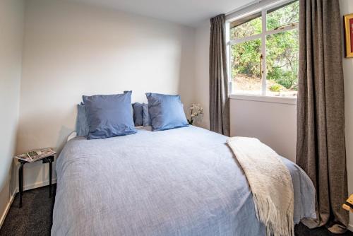a bedroom with a bed with blue pillows and a window at The Grandstand - French Farm Holiday Home in French Farm