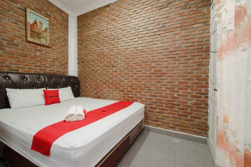 - une chambre avec un mur en briques et un lit avec des chaussons dans l'établissement RedDoorz Syariah near Jalan Asahan Pematang Siantar, à Pematang Siantar