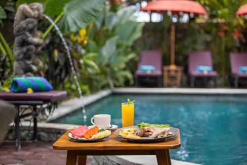 a tray of food on a table next to a pool at Uma Sari Cottage by Mahaputra in Ubud