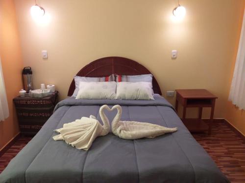 two swansrendered to look like birds sitting on a bed at Hostal Real Divina in Juliaca