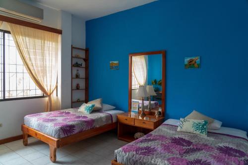 Habitación azul con 2 camas y espejo. en Mare Mio, en Puerto Baquerizo Moreno