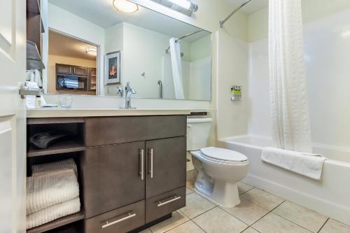 a bathroom with a toilet and a sink and a tub at Candlewood Suites Lincoln by IHG in Lincoln