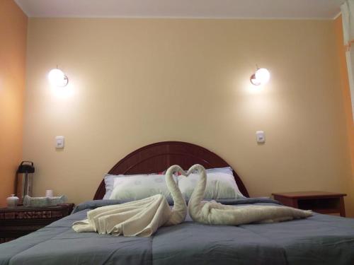 dos cisnes sobre una cama en Hostal Real Divina, en Juliaca