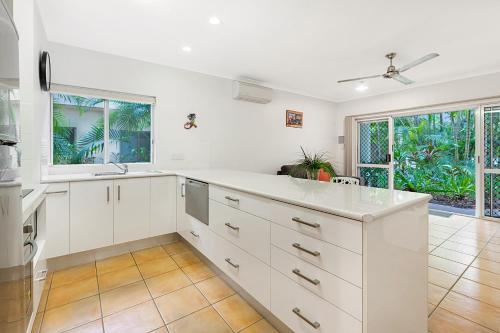 una cocina vacía con armarios blancos y ventanas en Outrigger Apartments Port Douglas en Port Douglas