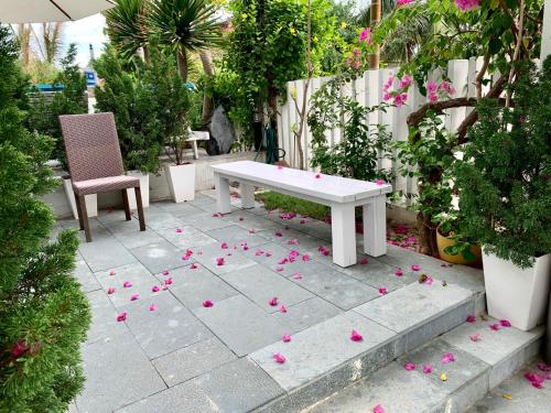 a white bench and some pink flowers on a patio at Santa Sea Villa in Hoi An